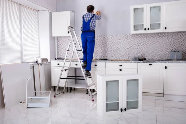 Vista Traseira Carpinteiro Masculino Que Monta Armário Branco Parede Cozinha — Fotografia de Stock