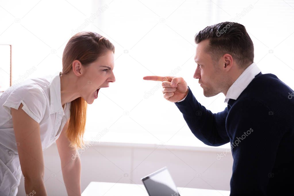 Side View Of Businessman Pointing Finger At Businesswoman While Fighting In Office