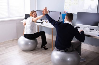 İşadamı ve iş kadını ofis yüksek beş veren fitness Ball oturan
