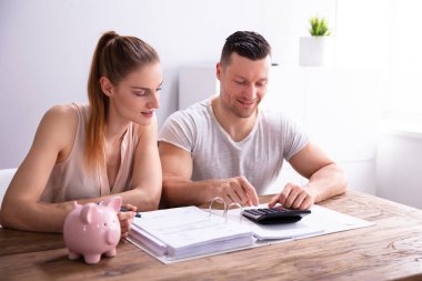 Çift İşyerinde Piggy Bank Yakınında Hesap Makinesi Kullanarak Faturaları Hesaplama