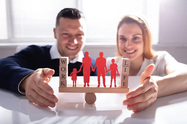 一对夫妇保护工作和生活平衡与家庭数字在办公桌上的跷跷板 — 图库照片