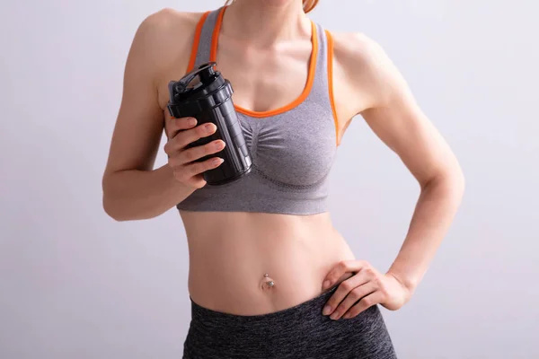 Porträtt Leende Fitness Kvinna Innehav Protein Shaker Flaska Mot Grå — Stockfoto