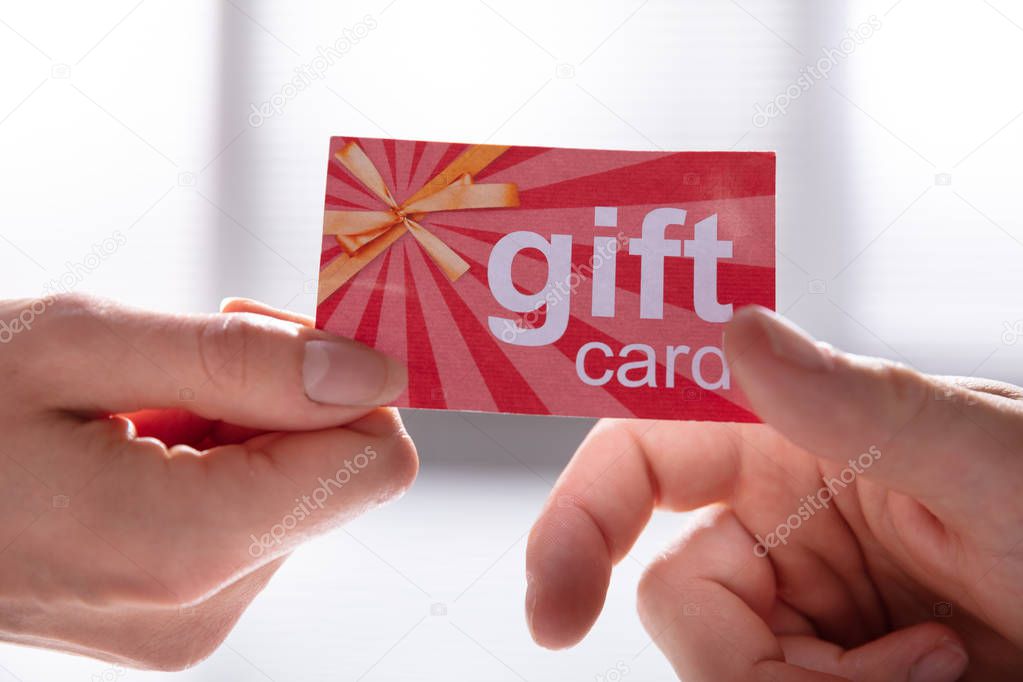 Close-up Of Female Hand Giving Gift Card To Her Male Partner