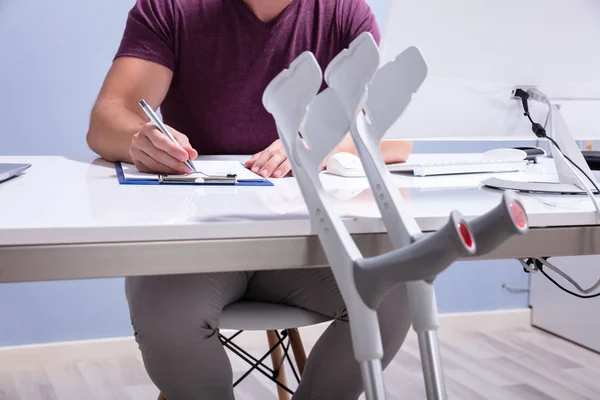 Close Crutches Leaning Table Front Handicapped Man Filling Form — Stock Photo, Image