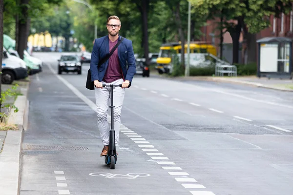 一个年轻的商人在城市的道路上骑电动滑板车的肖像 — 图库照片