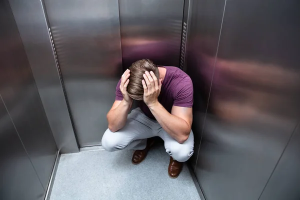 Crouched Worried Man Hands Head Elevator — Stock Photo, Image