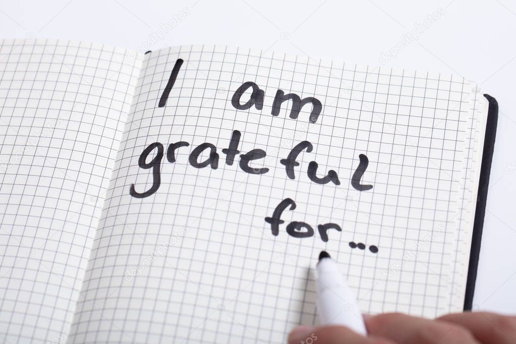 Close-up Of A Person Writing I Am Grateful For Text In Notebook With Black Marker