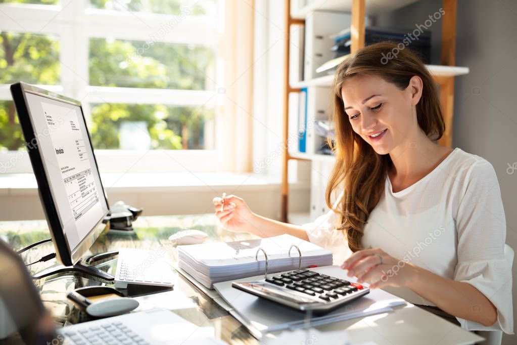 Smiling Businesswoman's Hand Calculating Bill In Office