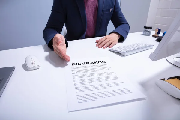 オフィスのホワイトデスクの上に保険書類を示すビジネスマンの中間セクション — ストック写真