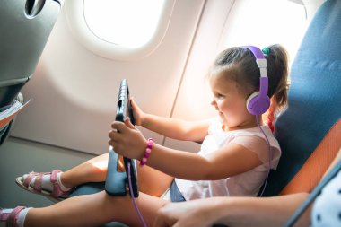 Uçakla Seyahat Sırasında Dijital Tablet Kullanarak Başının Üstünde Kulaklık ile Adorable Little Girl