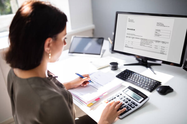 Businesswoman calculating tax at desk in office