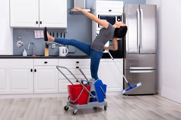 台所で床を掃除しながら滑る若い女性のクローズアップ — ストック写真