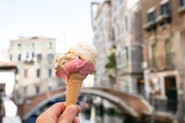 Osoba Rękę Trzymając Ice Cream Cone Przed Niewyraźne Stare Domy — Zdjęcie stockowe