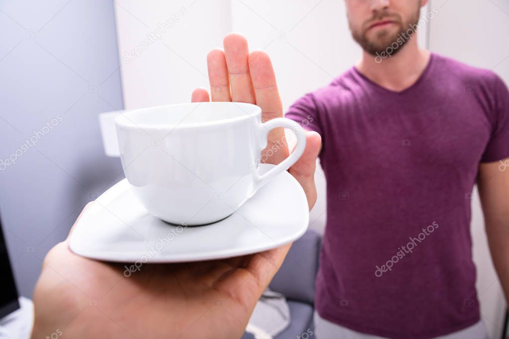 Close-up Of A Man's Hand Refusing Cup Of Coffee Offered By Person