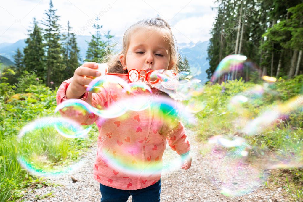 Girl Blowing Bubbles On A Sunny Day In Park