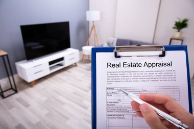 Close-up Of A Person's Hand Filling Real Estate Appraisal Form With Pen clipart