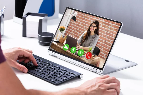 Businessman Video Conferencing With His Colleague On Hybrid Laptop On Desk In Office