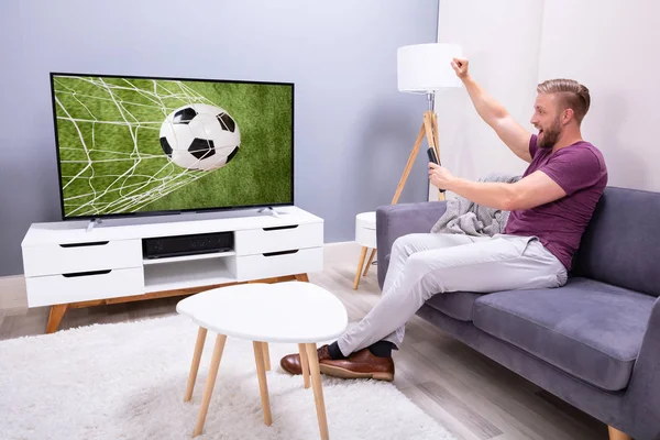 男人坐在沙发上看电视足球比赛在家里 — 图库照片