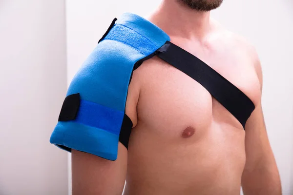 Shirtless Man With A Ice Pack On His Shoulder Standing Against Wall — Stock Image Shirtless Man Ice Pack His Shoulder Standing Wall Stock Image