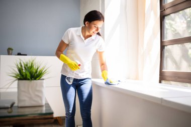 Genç kadın pencere pervazına peçete ve püskürtülen ilaç şişe Office ile Temizleme