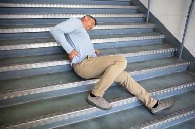 Olgun bir adam merdivenlerde kayıp düştükten sonra yatıyor.
