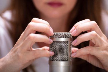 Asmr sesleri yapmak için mikrofonu çivilerle tırmalayan kadın