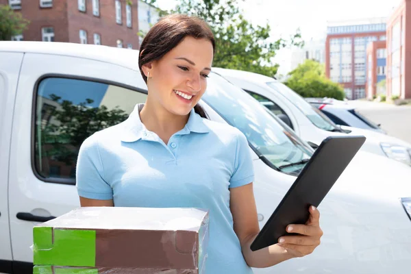 Smiling Delivery Woman Holding Cardboard Box Using Digital Tablet