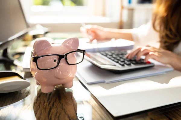 Businessperson Beräknar Räkningen Framför Pink Piggy Bank Över Skrivbordet — Stockfoto