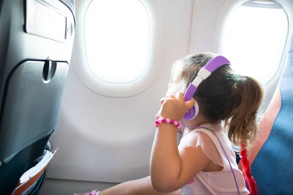 Klein Meisje Reist Vliegtuig Luisteren Naar Muziek Paarse Hoofdtelefoons — Stockfoto