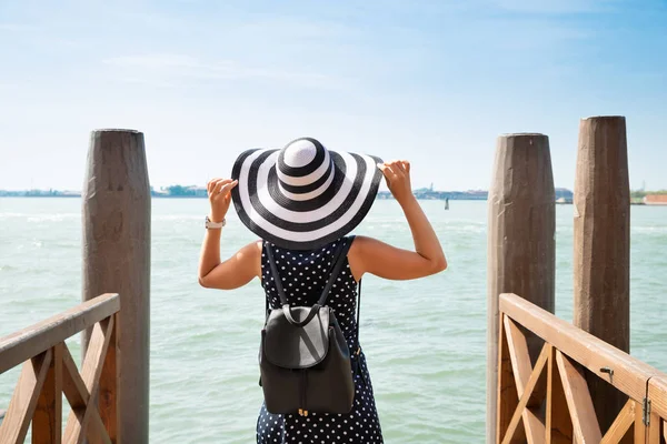 后视图的妇女与她的背包站在木码头俯瞰海湾 — 图库照片
