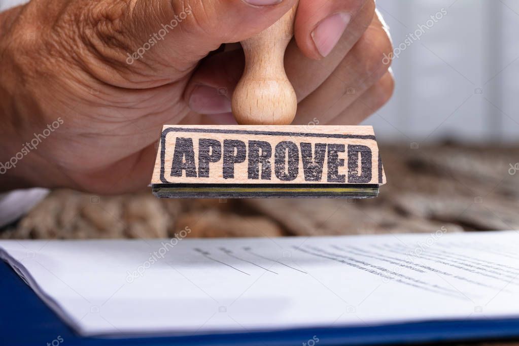 Close-up Of Person Hands Pressing Stamper On Document