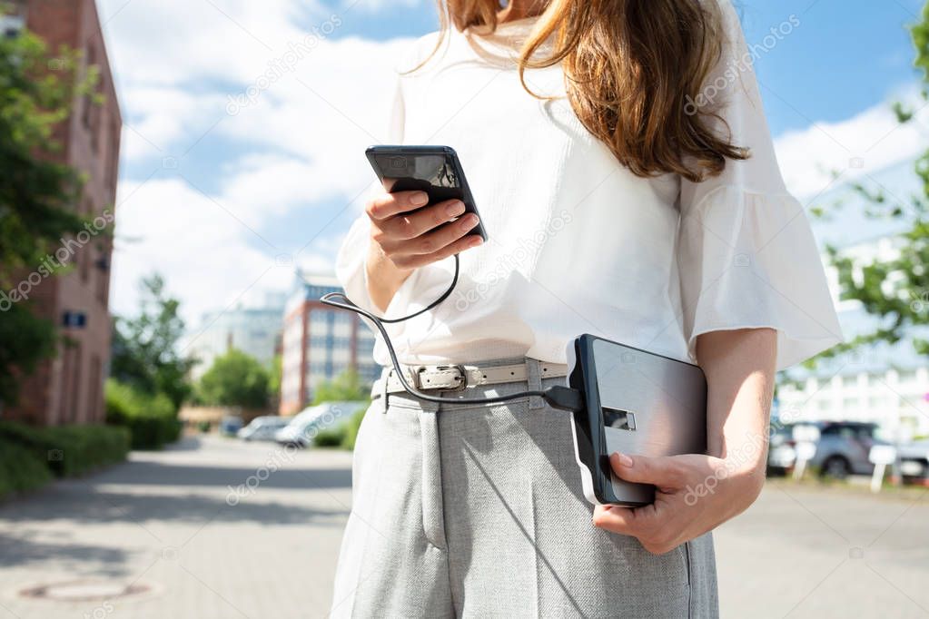Closeup Of Woman Holding Mobile Phone And External Battery
