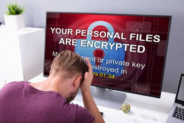 Worried Businessman At Computer With Ransomware Word On The Screen At The Workplace clipart