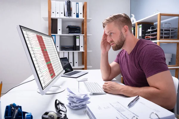 Despairing Businessman Faced With Financial Losses Looking On Graphs Dropping Into The Red