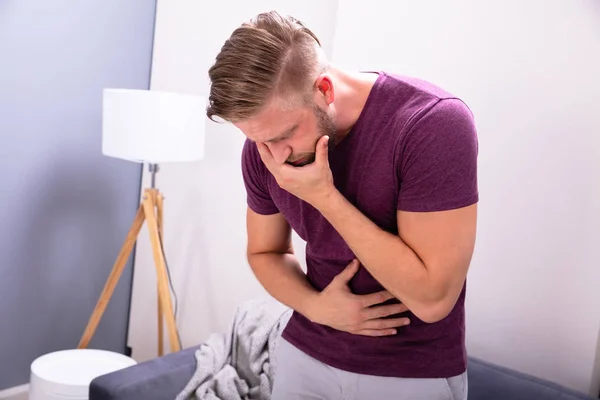 Giovane Uomo Che Soffre Nausea Piedi Davanti Divano Casa — Foto Stock