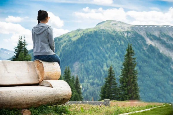 坐在长凳上享受全景山景的女人 — 图库照片