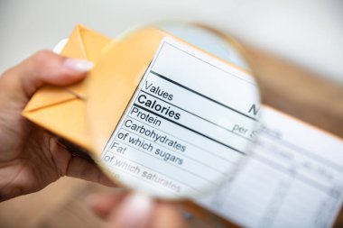 Bir Kişi Büyüteç ile Paket Üzerinde Beslenme Gerçekler Arıyorsunuz