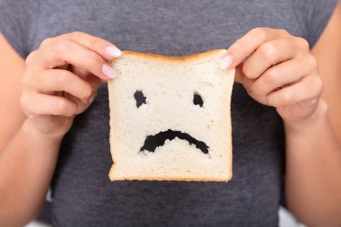 Mid-section Of A Woman Hands Holding Sliced Bread With Unhappy Face Cut Out clipart