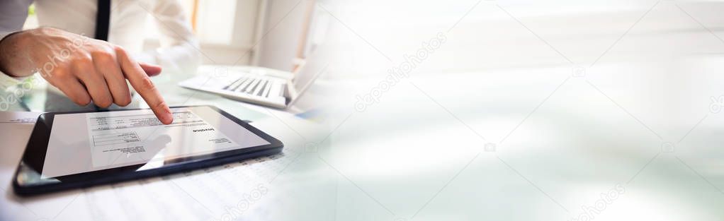 Close-up Of Businessman Using Digital Tablet For Calculating Invoice At Office