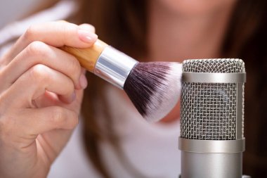 Asmr sesleri yapmak için mikrofonda fırça kullanan kadın