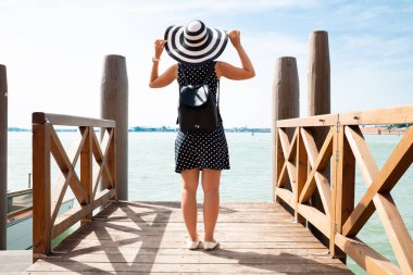 Koya bakan ahşap iskelede duran sırt çantası ile kadının arka görünümü