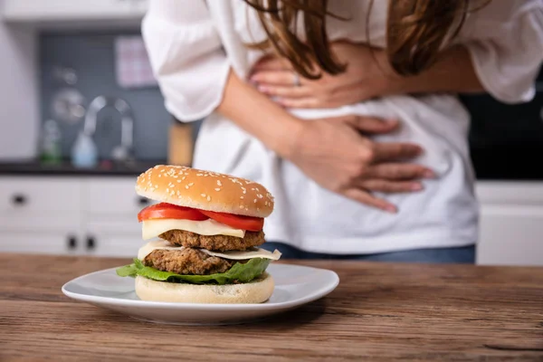 Mittelteil Der Frau Leidet Unter Bauchschmerzen Beim Burger Essen — Stockfoto