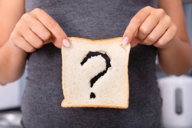 Mid-section Of A Woman Hands Holding Sliced Bread With Question Mark Sign clipart