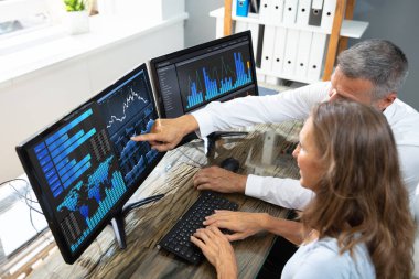 İş yerindeki dizüstü bilgisayardaki grafikleri analiz eden erkek ve kadın borsa simsarı yan görünümü