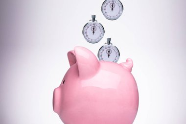 Close-up Of Pink Piggy Bank With Stopwatch Against White Background clipart
