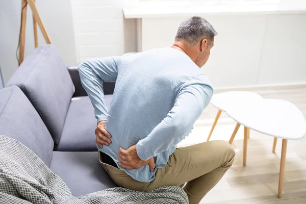自宅で背中の痛みに苦しむソファの男 — ストック写真
