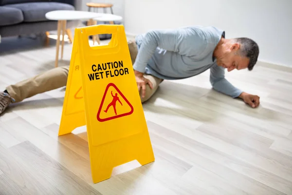 Mature Man Falling Wet Floor Front Caution Sign Home — Stock Photo, Image