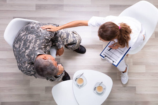 An Elevated View Of Female Councilor Consoling Soldier At Her Clinic