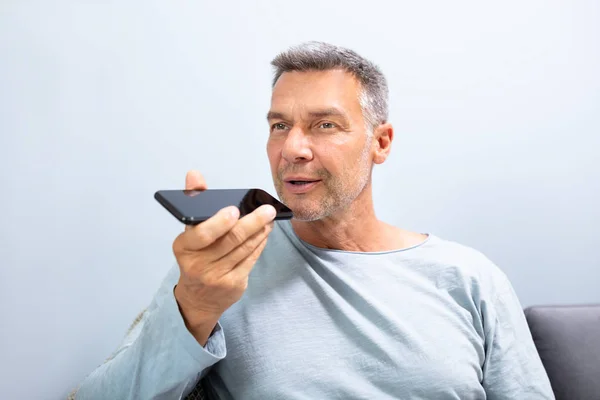 一个胡子男子在白色背景下使用手机语音识别功能的特写 — 图库照片