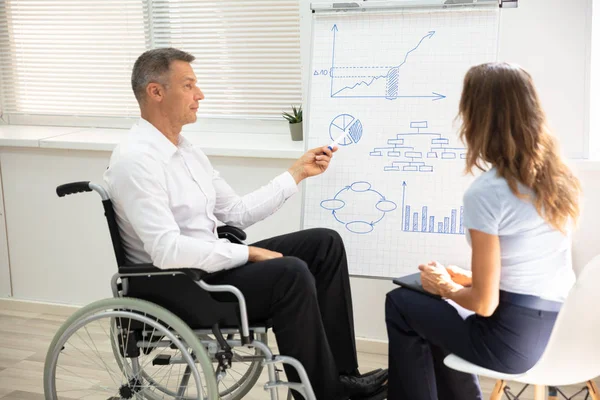 Niepełnosprawny Dojrzały Biznesmen Pokazując Diagram Podczas Dając Prezentacja Swojego Kolegę — Zdjęcie stockowe